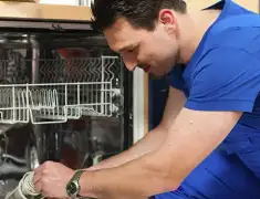 Dishwasher repair technician inspecting and servicing an open dishwasher in Mesa, AZ