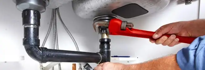 Garbage disposal repair technician tightening the sink drain and disposal connection in Mesa, AZ