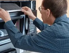 Appliance repair technician replacing a microwave vent filter in Mesa, AZ