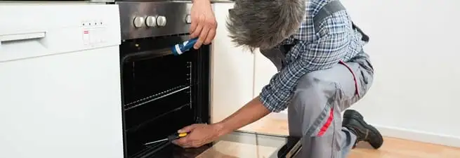 Oven repair technician inspecting and servicing an electric oven in Mesa, AZ