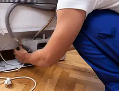 Appliance repair technician fixing refrigerator water line and connections in Mesa, AZ