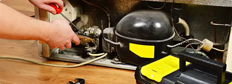 Refrigerator repair technician fixing the compressor and wiring in Mesa, AZ
